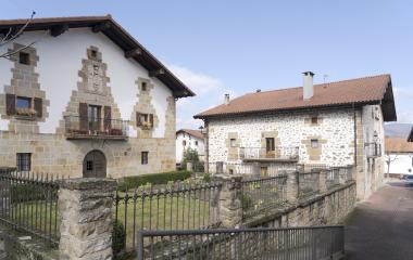 Casas de piedra y arquitectura tradicional en Iturmendi con escudo en la fachada y jardin con huerta.