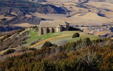Ermita medieval de piedra en Izagaondoa con vistas panorámicas a campos de cultivo y bosques del prepirineo navarro.