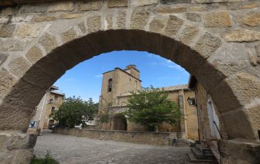 Arco de piedra arenisca enmarcando iglesia de Leache.