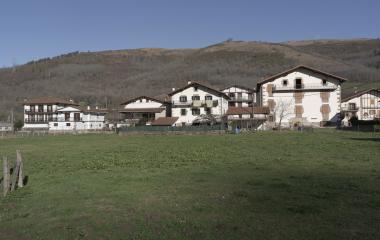 Conjunto de casas de Legasa con montañas de fondo y prados de pastoreo.