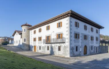 Casa Antonenea en Lekunberri, con fachada blanca y una torre de piedra.