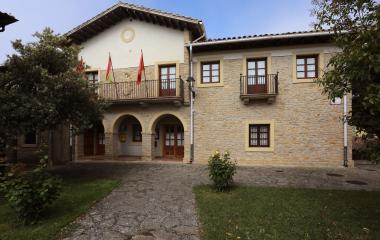 Ayuntamiento de piedra en Lerga con fachada de dos plantas, balconadas y banderas en balcón superior.