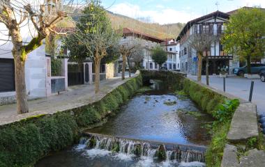 Rio atraviesa el pueblo de Lesaka con casas de piedra y torre a los lados.