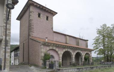 Iglesia de Lintzoain en el Pirineo navarro, con torre cuadrada de piedra  y portada de arcos.