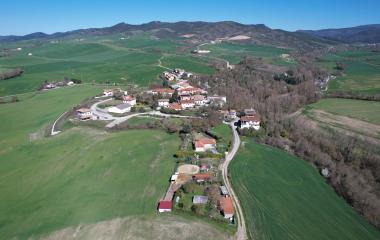 Vista aérea de Lizoain-Arriasgoiti con casas dispersas, campos verdes y bosques.