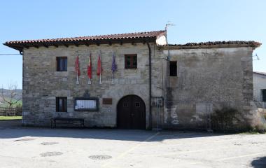 Ayuntamiento de piedra con banderas en Lizoain-Arriasgoiti, fachada principal con puerta de arco.