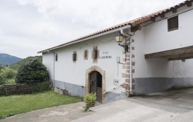 Casa Gardorena de arquitectura tradicional en Lusarreta, Pirineo navarro, con fachada blanca, jardin y muro de piedra.