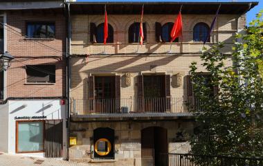 Fachada del ayuntamiento de Monreal con banderas, escudos en piedra y balconadas de hierro forjado.