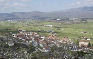 Vista panorámica de Ergoiena con caseríos de tejados rojizos, prados verdes y montañas al fondo en Sakana.