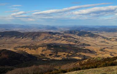 Valle extenso con campos de cultivo y bosques dispersos visto desde Higa de Monreal, montañas al fondo bajo cielo despejado.