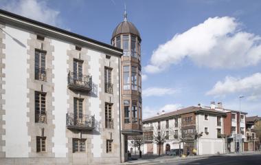 Edificio singular con torre cupulada y fachada de piedra en Olazti, rodeada de arquitectura tradiconal.