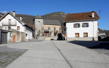 Plaza del pueblo de Orbara con iglesia de piedra, casas tradicionales blancas.