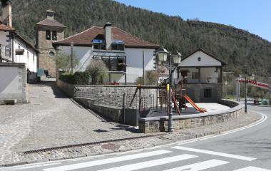 Plaza de Oronz con iglesia, casas de piedra y parque, rodeada de bosque.