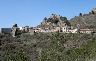 Pueblo de Petilla de Aragon asentado en ladera con casas tradicionales y formaciones rocosas al fondo.