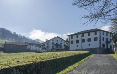 Prados verdes delante de un conjunto de casas del pueblo de Gartzain.