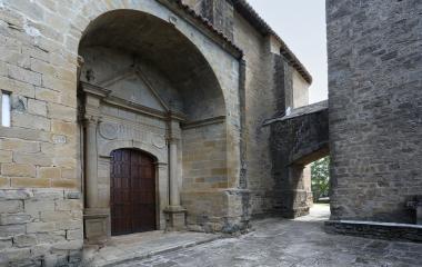 Portada de iglesia de San Vicente, en piedra arenisca con arco y puerta de madera oscura en Sada.