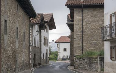 Calle asfaltada de Urdaniz con casas tradicionales de piedra o blancas en el Pirineo navarro.