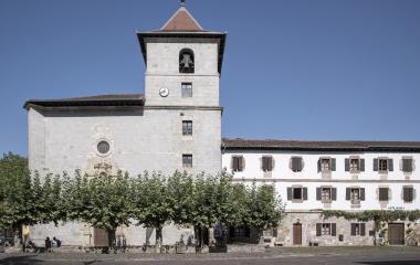Iglesia de Urdax con campanario de piedra clara, ventanas románicas y estructura arquitectónica religiosa tradicional vasca de varios pisos.