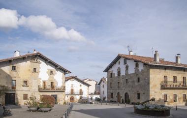 Plaza de Urdiain con casas de piedra y arquitectura tradicional bajo cielo nublado.