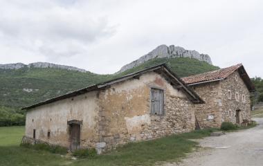 Caseríos de piedra tradicionales en Urdiroz con cortados calizos de montaña al fondo.