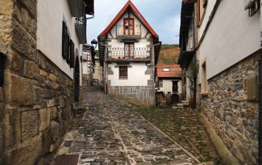 Calle empedrada de Uztarroz con casas de piedra y tejadillos rojos típicos de arquitectura pirenaica navarra.