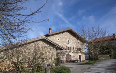 Casa rural de piedra en Atez con arquitectura tradicional navarra, árboles invernales y camino de acceso.