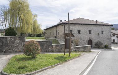 Casa de piedra tradicional en Odieta con muros y con un jardin y la carretera a los lados.