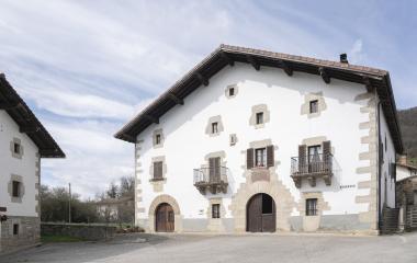 Casa tradicional de piedra y blanca en Odieta con fachada de silleria, balconies y puertas arqueadas de estilo vasco.