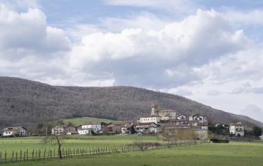 Un pueblo del valle de Ulzama rodeado de prados verdes y montes boscosos.