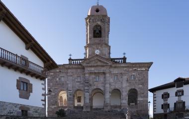 Fachada de la iglesia de Ziga con pórtico de arcos, escalinata central y torre campanario