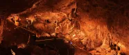 Cuevas de Mendukilo por dentro, con estalactitas y estalacmitas alumbradas con luces anaranjadas.