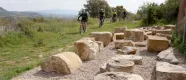 Grupo de ciclistas andando por el prado verde, al lado piedras.