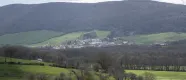 Valle de Ultzama con pueblo en prado verde rodeado de bosque y montañas boscosas de fondo.